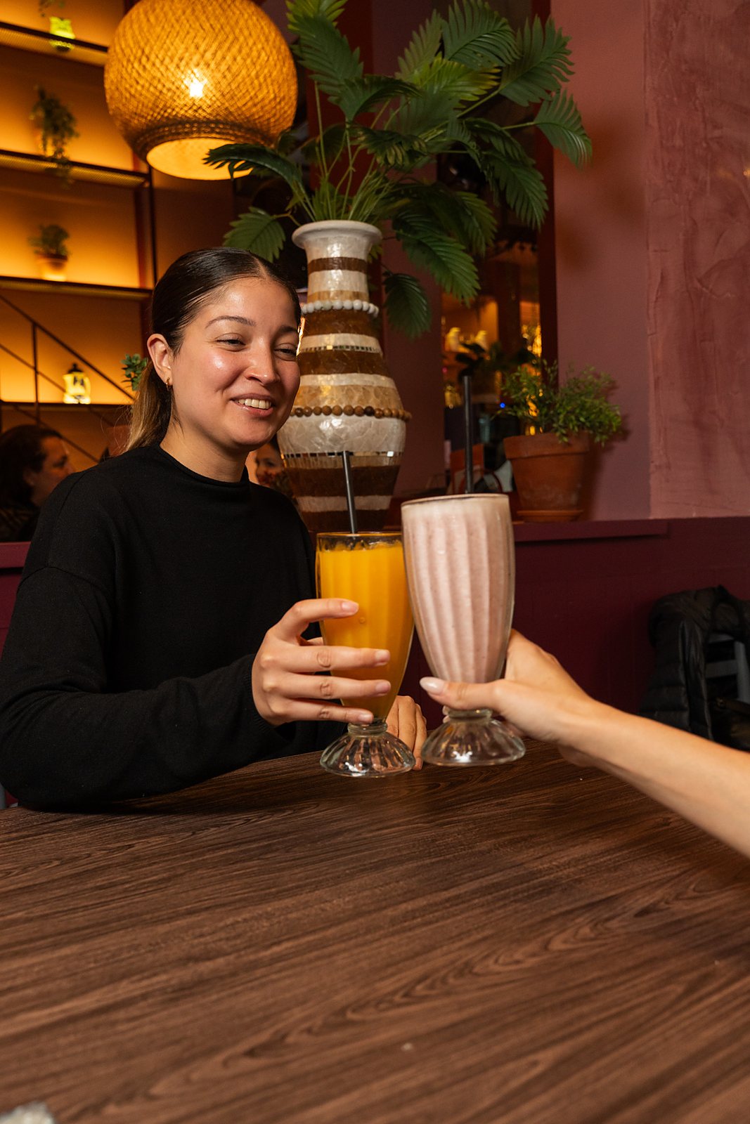 Una clienta brinda con un exprimido de naranja y un licuado