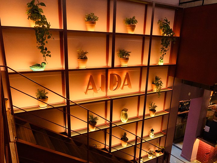 La escalera al primer piso, con la estantería iluminada y las letras AIDA