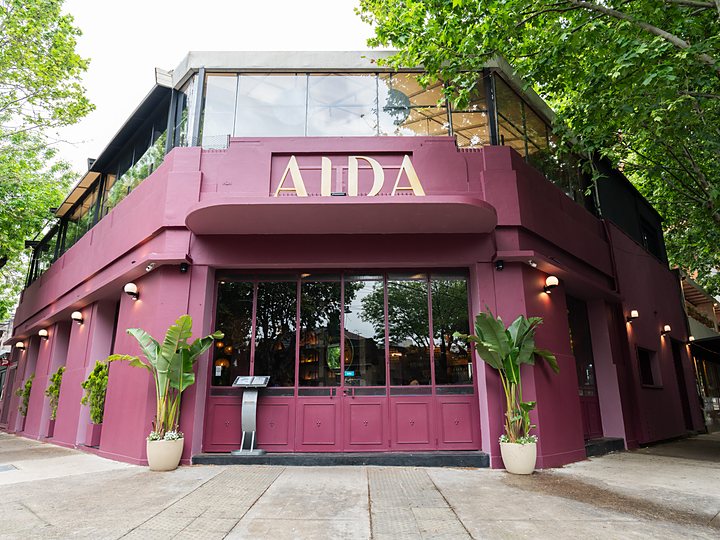 La fachada bordó de AIDA en la esquina de Pola, de día, con las letras doradas
